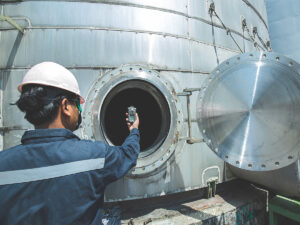 Workers holding up gas testing unit in confined space